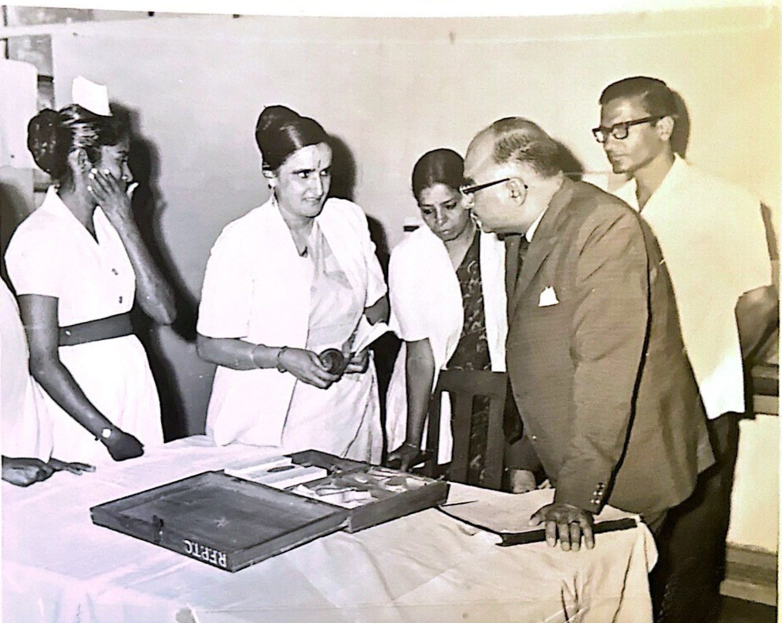 Dr. Rameshwari Sethi in a white sari with nursing staff, examining a tray of medical supplies